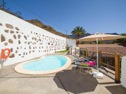 - une piscine avec un parasol et une chaise dans l'établissement Casa rural cercado de don paco, à Santa Lucía