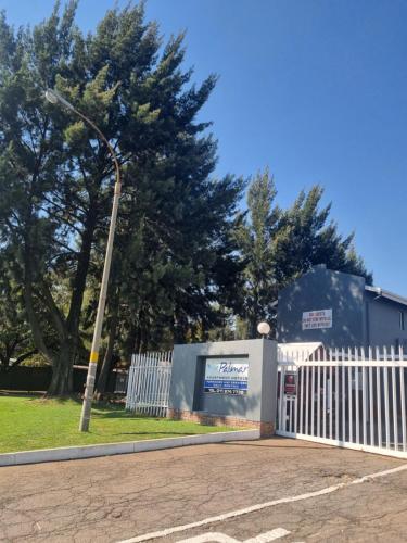 a white fence and a street light next to a building at Palmar Hotel in Johannesburg
