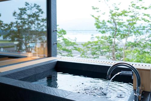 a bathroom with a bath tub with a window at Hotel Kitanoya in Miyazu