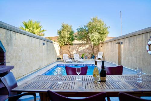 a table with a bottle of wine next to a swimming pool at 4 Bedroom Holiday Farmhouse with Private Pool in Għarb
