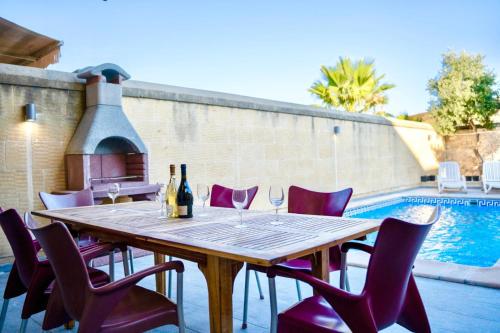 a table with wine glasses and purple chairs next to a pool at 4 Bedroom Holiday Farmhouse with Private Pool in Għarb