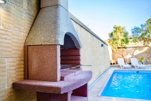 a outdoor pizza oven next to a swimming pool at 4 Bedroom Holiday Farmhouse with Private Pool in Għarb