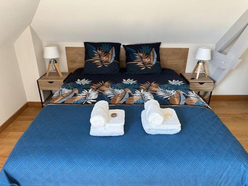 une chambre avec un lit bleu avec des serviettes dessus dans l'établissement La Tourelle, à Saint-Martin-le-Gréard