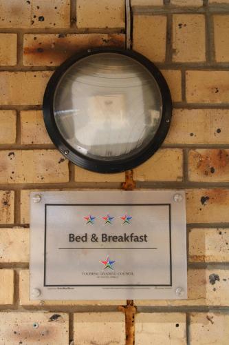 a sign on a brick wall with a bed and breakfast at Siyaya Sbosh BnB in Reitz