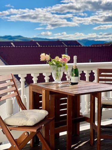 a table with a bottle of wine and flowers on a balcony at Toppleilighet Dr Holms in Geilo