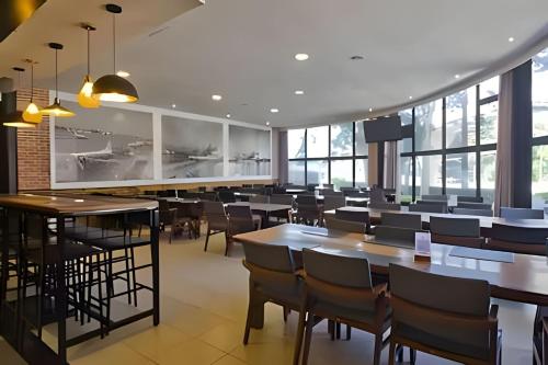 a restaurant with tables and chairs and windows at Airfamily Congonhas in Sao Paulo