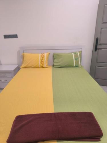 a bed with yellow and green sheets and pillows at Trinco Caritas Guest Villa in Trincomalee