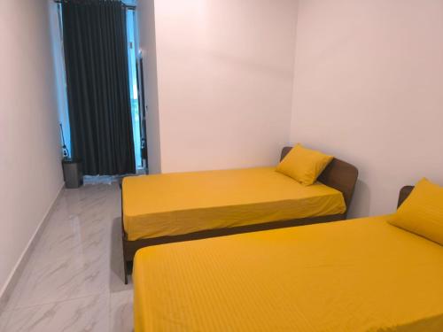 two beds in a room with yellow sheets at Trinco Caritas Guest Villa in Trincomalee