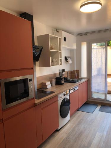 une cuisine avec des armoires rouges et un appareil blanc dans l'établissement Appartement Chaleureux -Paris-CDG-RER B-Parc des Expos de Villepinte-Disneyland-Asterix-Stade de France-, à Vaujours