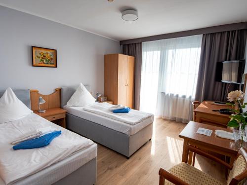 Una habitación de hotel con dos camas y un escritorio. en Alga Baltic Resort, en Świnoujście