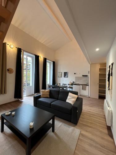 un salon avec un canapé noir et une table dans l'établissement Résidence Les 4 Quais, à Bordeaux