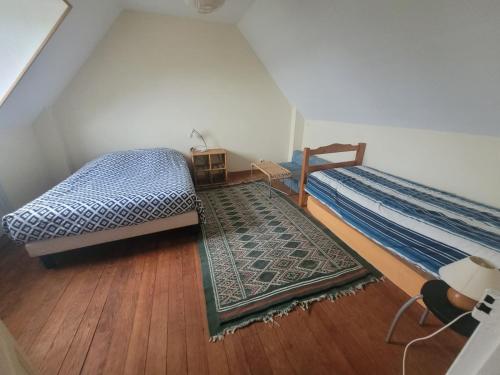 - une chambre avec 2 lits et un tapis sur du parquet dans l'établissement Maison de vacances à Roscanvel, à Roscanvel