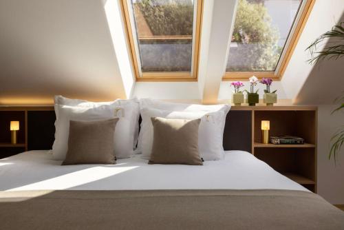 a bedroom with a bed with white pillows and two windows at Palace Natali in Dubrovnik