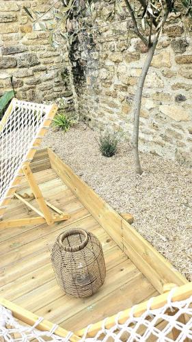 une terrasse en bois avec un panier à côté d'un mur de pierre dans l'établissement La maison du Pays d'Auge, à Troarn