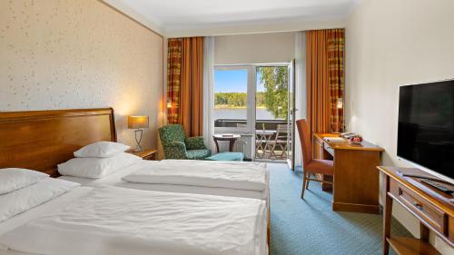 a hotel room with two beds and a television at Seehotel Mühlenhaus in Chorin