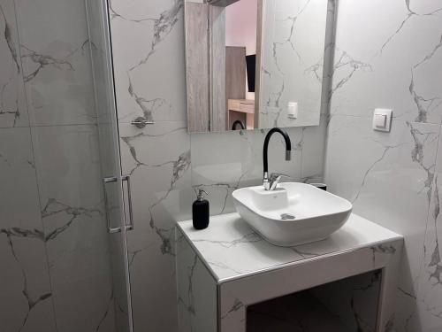 a white bathroom with a sink and a mirror at Naria Studios in Skala Fourkas