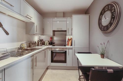 Una cocina con gabinetes blancos y un reloj en la pared. en 3, Gainsborough House, en Cheltenham