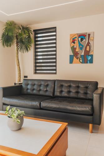 a black leather couch in a living room with a palm tree at Nos Aqua Villas Chania in Pazinos