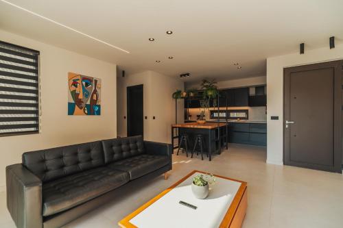 a living room with a black couch and a kitchen at Nos Aqua Villas Chania in Pazinos