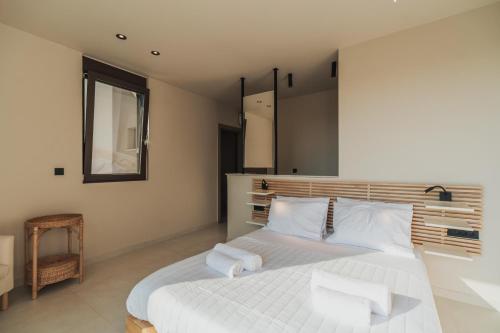 a bedroom with a bed with white sheets and a mirror at Nos Aqua Villas Chania in Pazinos