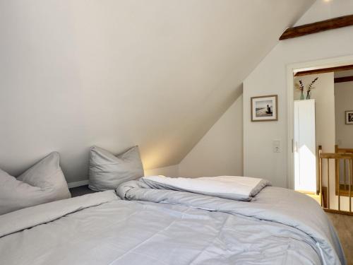 a bed with white sheets and pillows in a room at Friesenhus - Jever in Jever