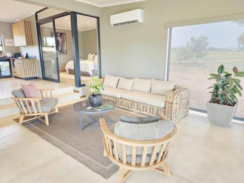 Simbini Sunset Cottage في ماليلين: غرفة معيشة مع أريكة وكراسي وطاولة