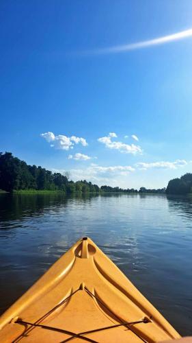 a yellow kayak in the water on a river at Oaza Święty Spokój - domek z balią i jacuzzi in Rząśnik