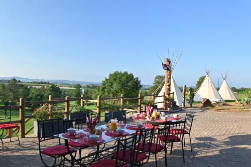 Un grupo de mesas y sillas con carpas al fondo. en LES CHAMBRES DE L'OUEST, en Longessaigne