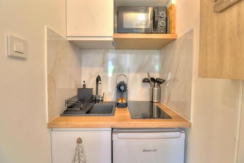 une petite cuisine avec une cuisinière et un micro-ondes dans l'établissement Charmant Studio rénové à Antibes, plage à 10 min à pied, à Antibes