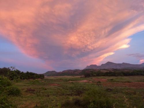 a cloud formation in the sky over a field at Cure Monastery Family Resort in Marayoor