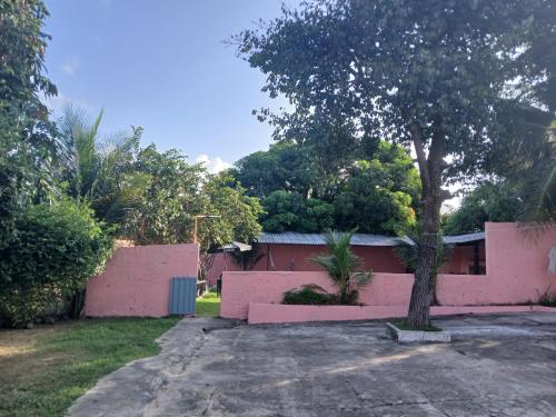 a pink house with a tree in front of it at Pousada Malibu-Salinas in Salinópolis