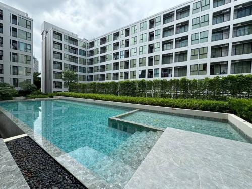 a swimming pool in front of a large building at Modern Condo Near Icon Siam & BTS Krung Thonburi in Bangkok