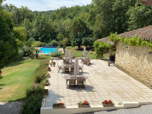 un patio avec des tables et des chaises dans un jardin dans l'établissement Le Clos Sainte Marie - Lampy, à Cenne-Monestiès