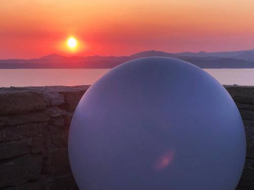 een grote witte bol met een zonsondergang op de achtergrond bij ARIA Kea Sunset Homes in Ioulida