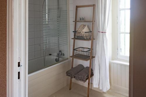 - une salle de bains avec une étagère en bois à côté d'une douche dans l'établissement Le Petit Gîte - La Nouvelle Histoire, à Graignes