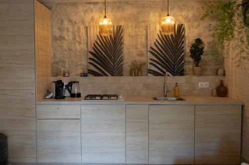 - une cuisine avec un plan de travail, un évier et deux lumières dans l'établissement Le Petit Gîte - La Nouvelle Histoire, à Graignes