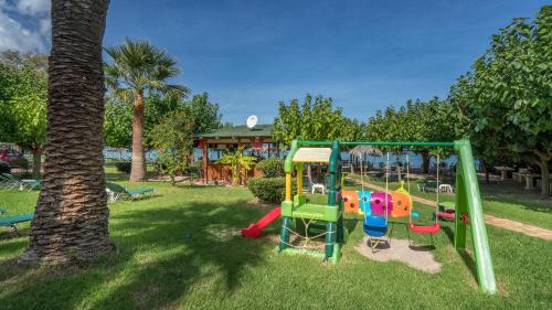 a playground in a park next to a tree at Levantino Studios & Apartments in Vasilikos