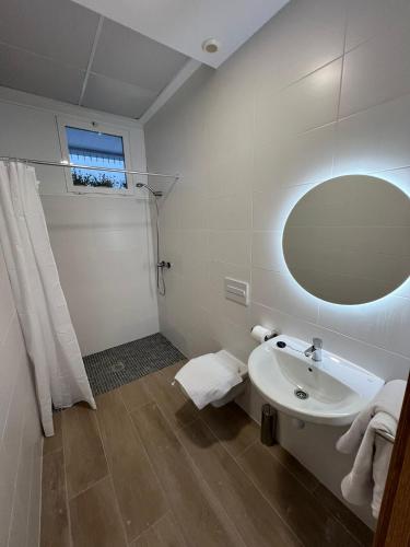 a white bathroom with a sink and a mirror at Apartamentos del Raval in Gandía