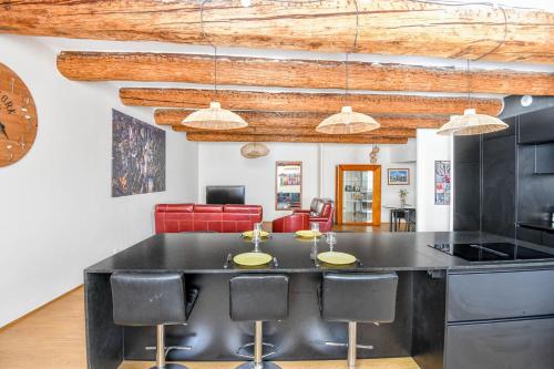 une cuisine avec un grand îlot noir et des tabourets de bar dans l'établissement Appart standing avec 2 ch clim sur le Vieux-Port, à Marseille