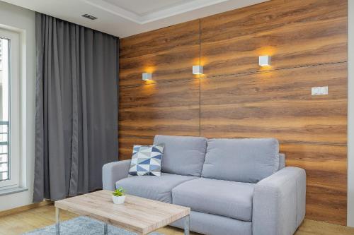 シュチェチンにあるPark Apartamenty Mariacka Szczecin z Parkingiem by Noclegi Rentersのソファ付きのリビングルーム、木製の壁