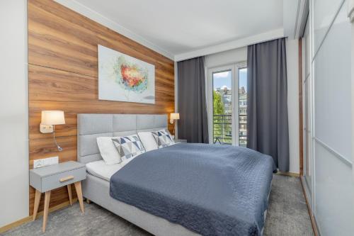 シュチェチンにあるPark Apartamenty Mariacka Szczecin z Parkingiem by Noclegi Rentersの青いベッドと窓のある寝室