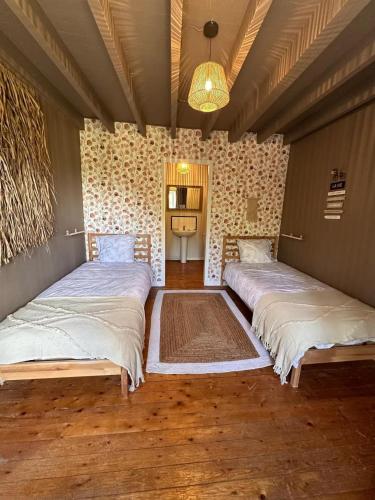 une chambre avec 2 lits et une lampe dans l'établissement Le Petit Gîte - La Nouvelle Histoire, à Graignes