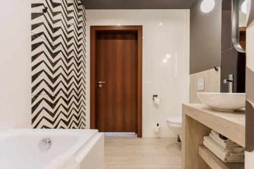 a bathroom with a sink and a toilet and a door at Hotel Tarnovia in Tarnów