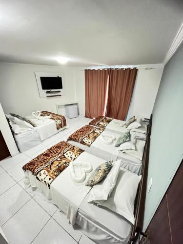a hotel room with three beds and a flat screen tv at Pousada Verdes Mares in Maragogi