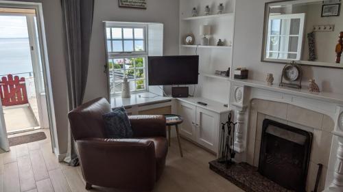 a living room with a fireplace and a chair and a television at Widows Row Cottage in Newcastle