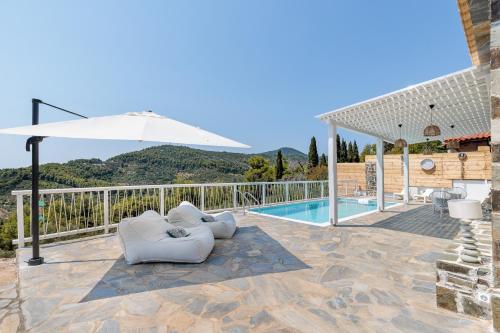 a patio with two chairs and an umbrella next to a pool at Villa Zoe in Panormos Skopelos