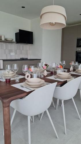 a dining room with a table with chairs and wine glasses at Vakantiewoning 'Tranquille' Kortenaken in Kortenaken