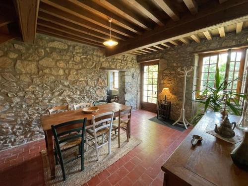une salle à manger avec une table et un mur en pierre dans l'établissement Charmante Maison dans le Morvan, à Montsauche