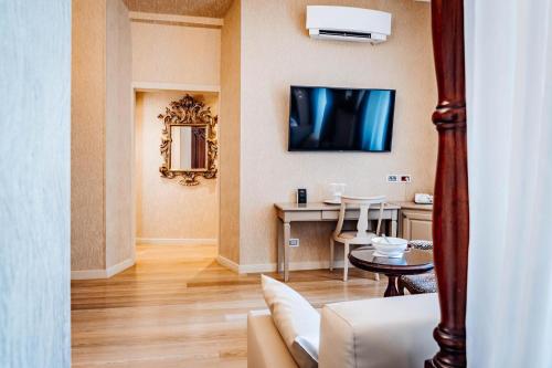 a living room with a couch and a tv on the wall at Hotel Villa Madruzzo in Trento