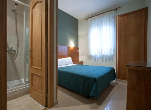 um quarto com uma cama e um chuveiro de vidro em Hostal Zabala em Madrid